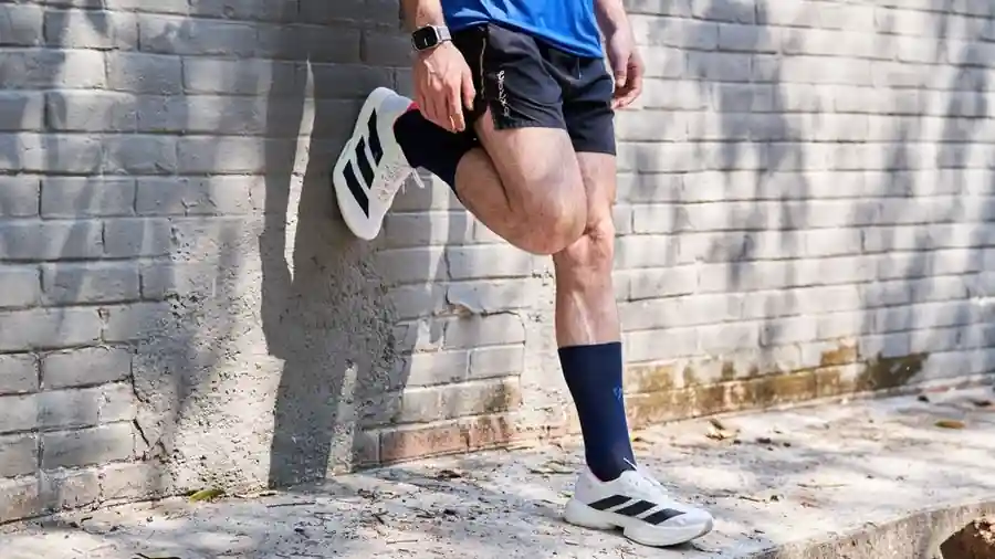 벽에 손을 짚고 뒷다리를 뻗어 종아리를 늘이는 사람