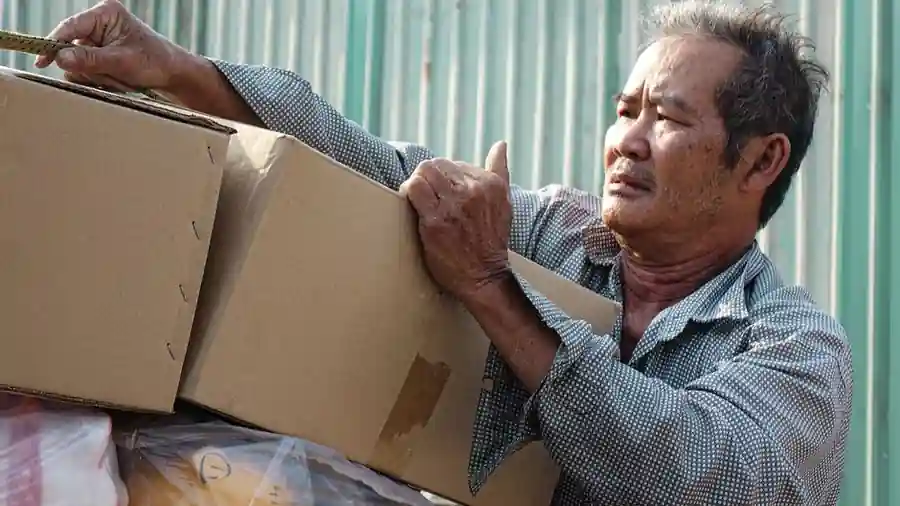 무거운 상자를 들어 올리는 작업자